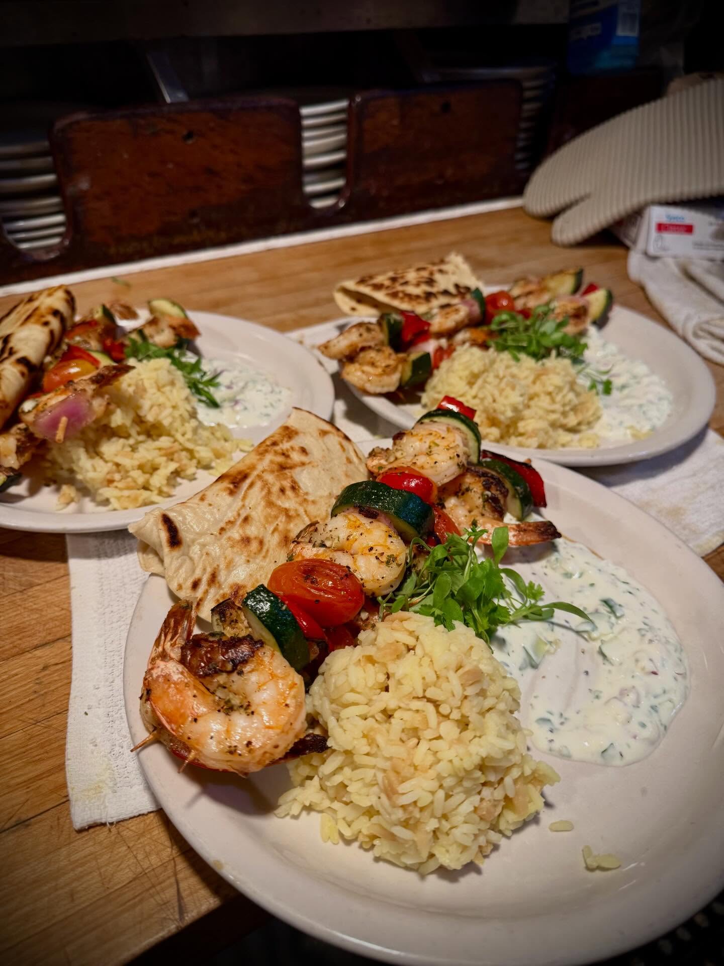 grill shrimp skewers with rice pilaf, pita, tomato, onion, and tzatziki sauce